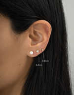 Close-up of an ear wearing three earrings with measurements indicated.
