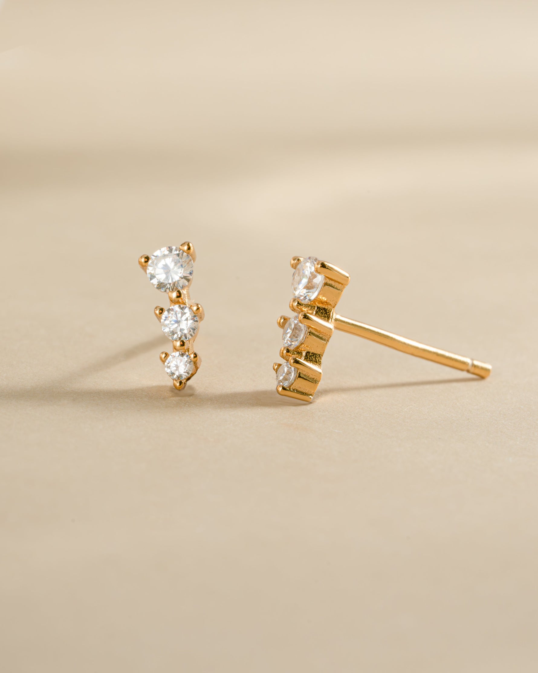 Close-up of gold CZ ear climber earrings by Sami Jewels with sparkling diamonds on a white background.