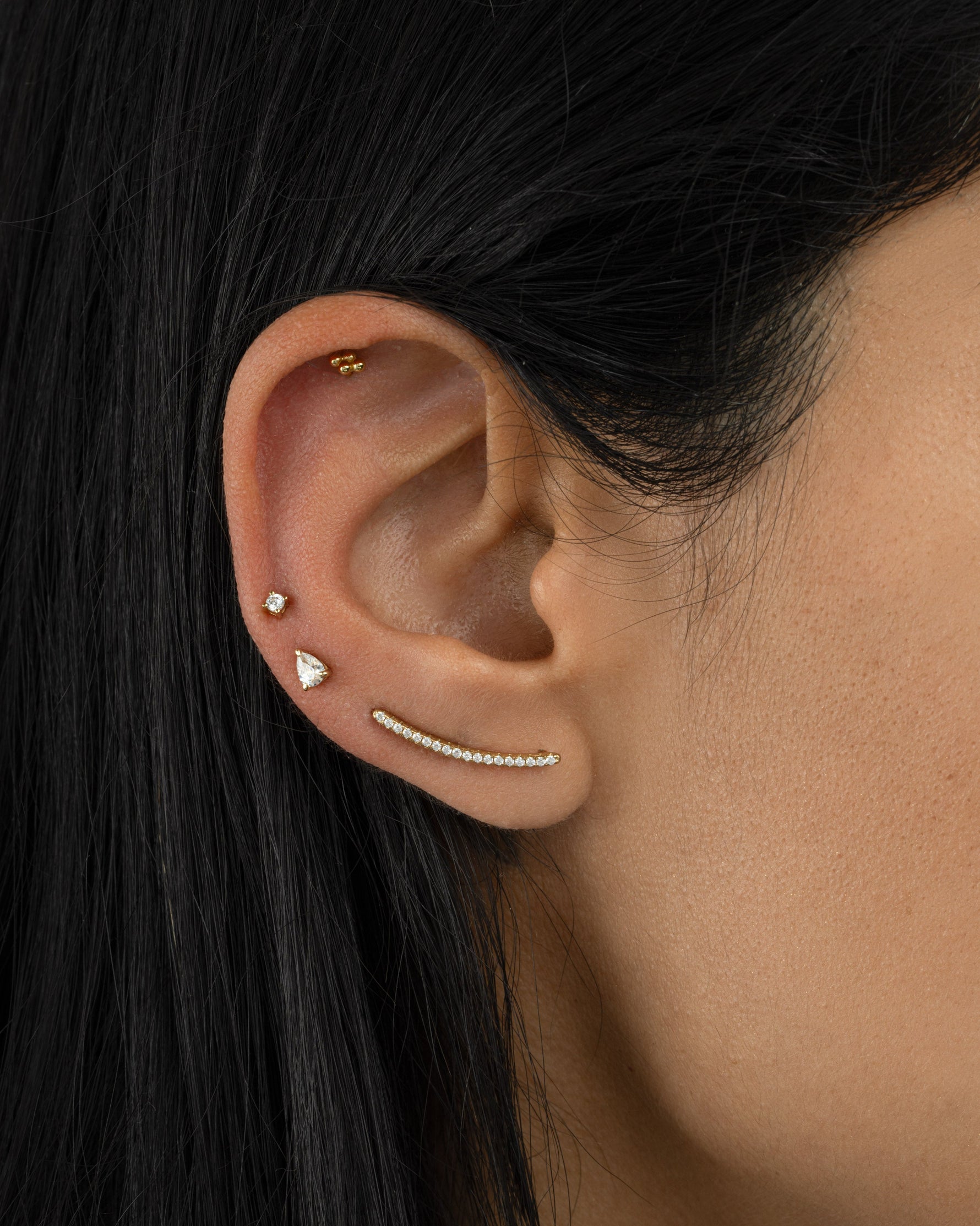 Gold studded ear climber earrings with diamond accents by Sami Jewels worn on a model's ear.