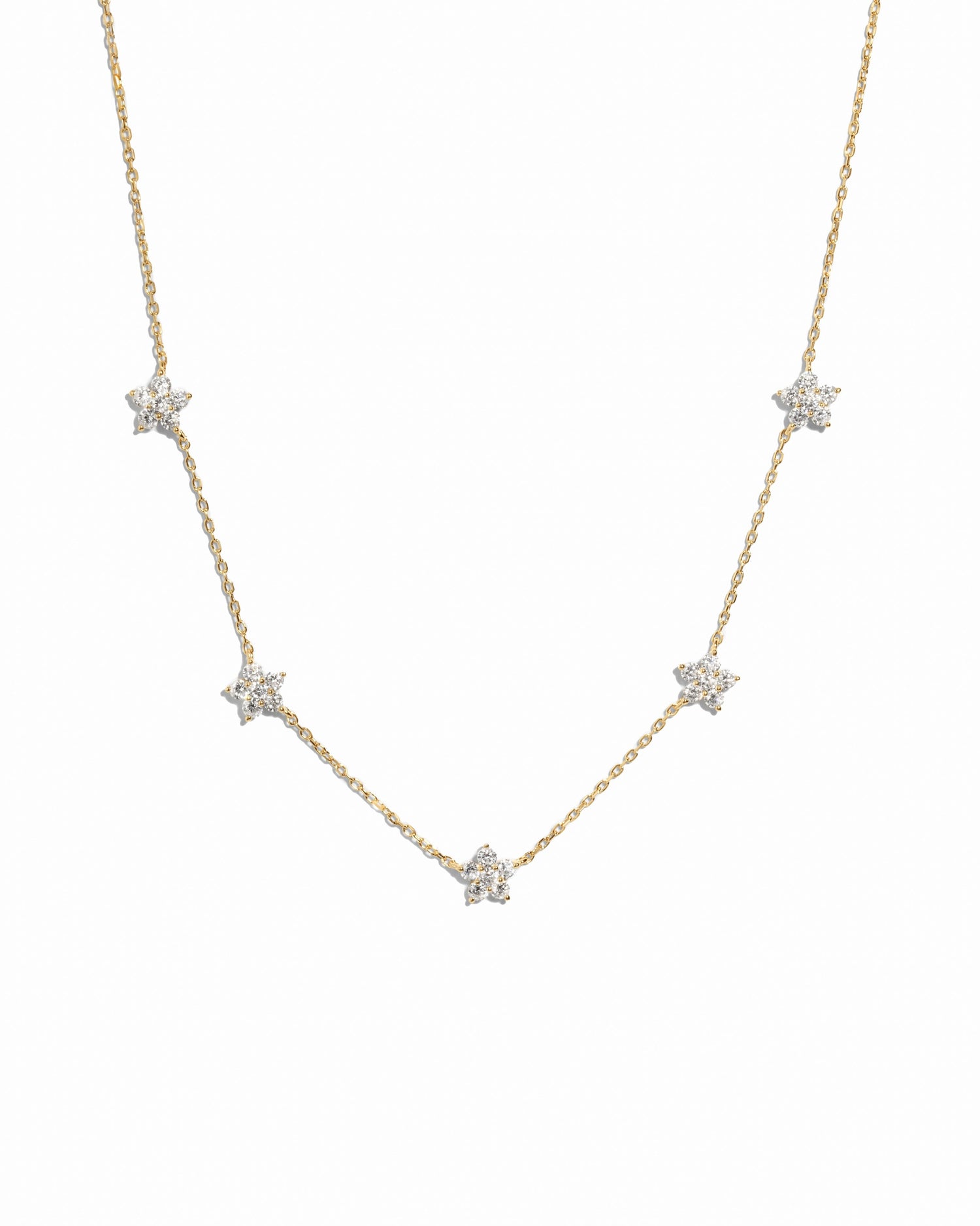 Gold diamond flower necklace by SJ Faire featuring a delicate floral charm on a chain, displayed against a white background.