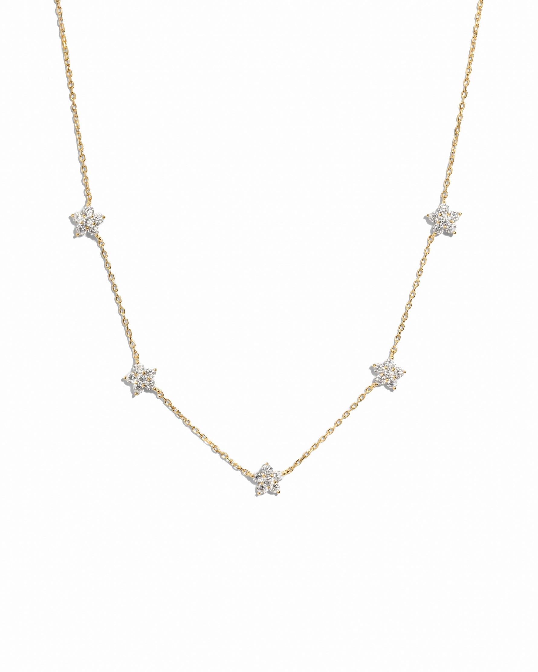 Gold diamond flower necklace by SJ Faire featuring a delicate floral charm on a chain, displayed against a white background.