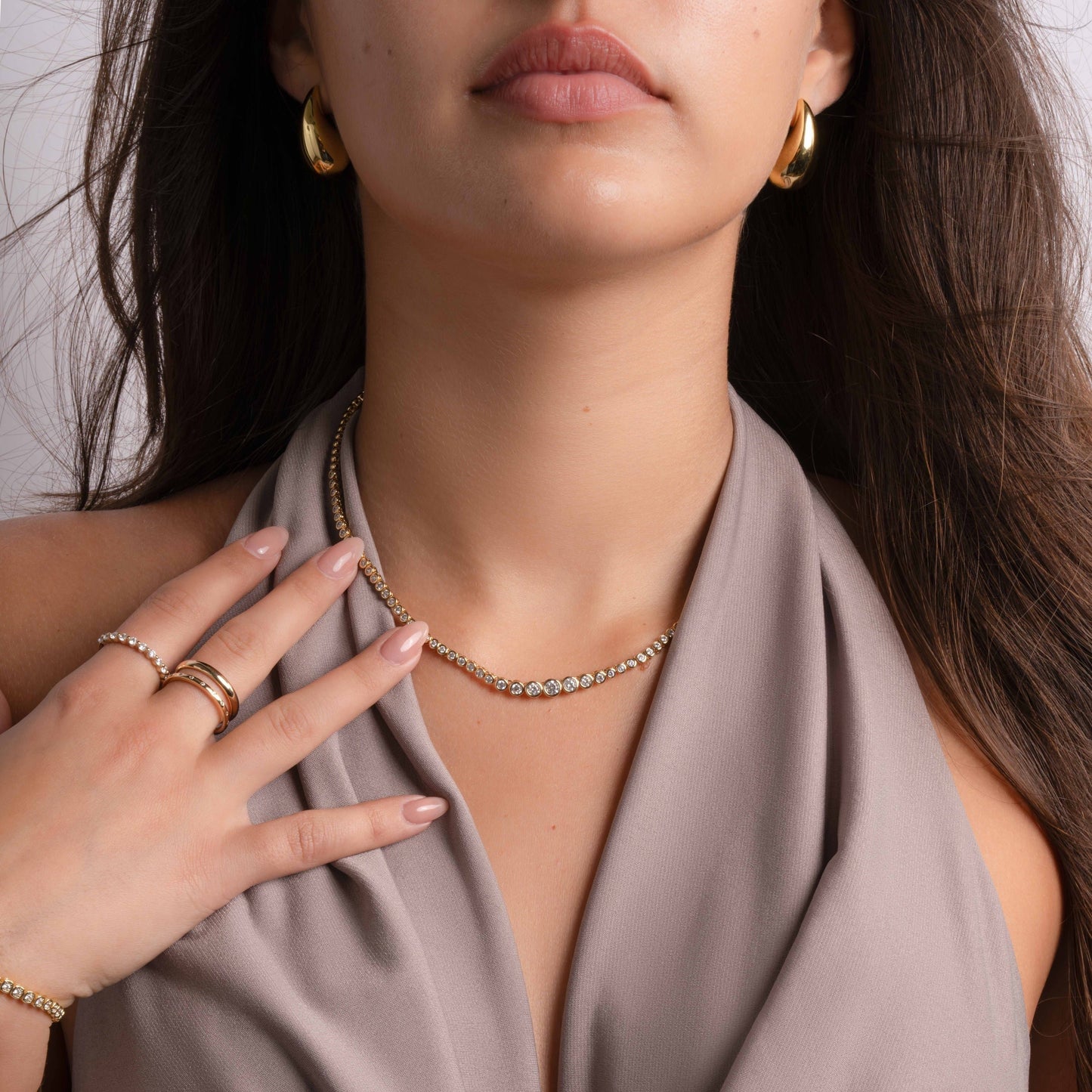 model wearing a gold chain with tiny  diamond beads along with dainty diamond ring on her index finger and gold double band on her long finger.