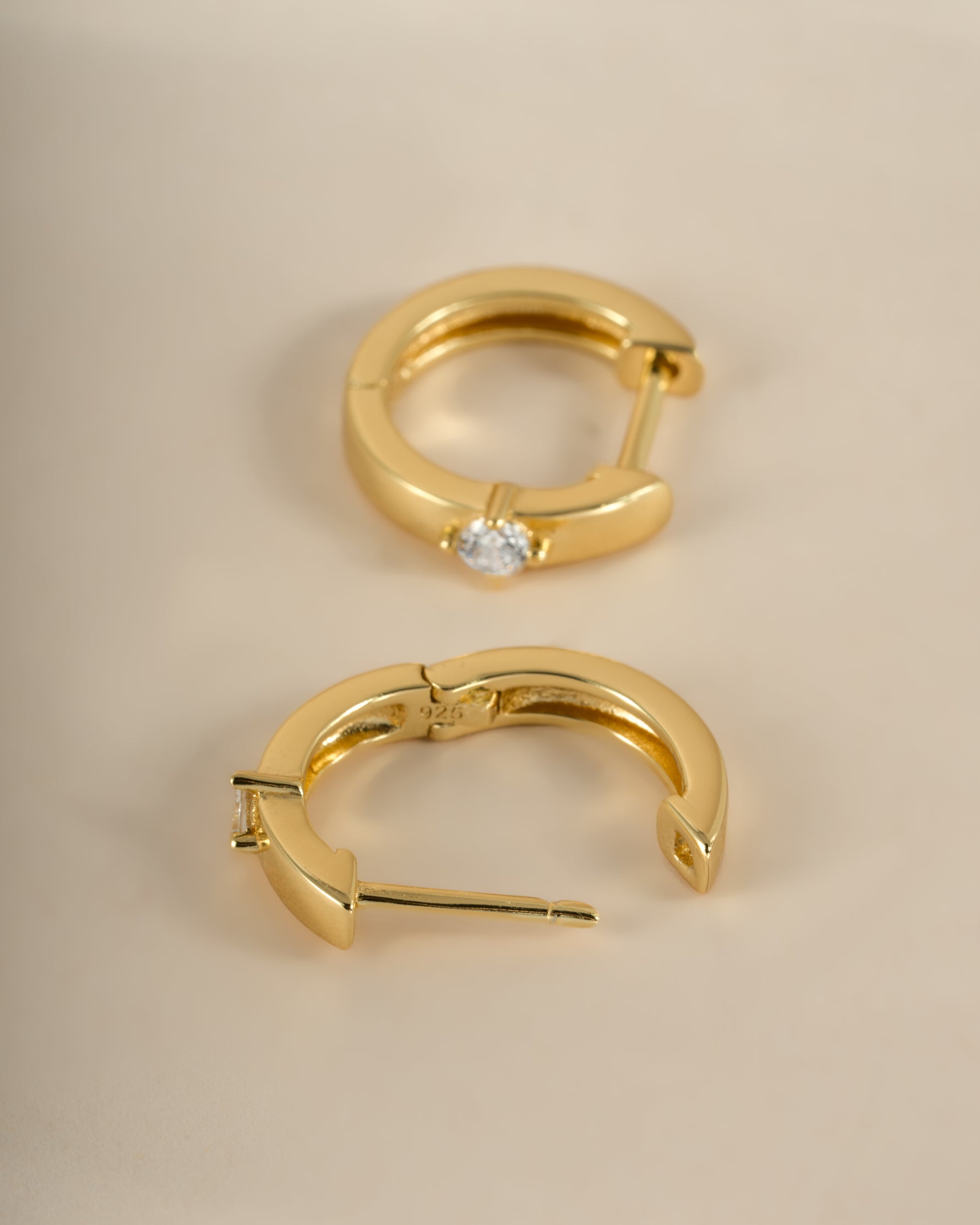 Gold diamond-huggie hoop earrings from Sami Jewels displayed from an angled view, showcasing their elegant design and sparkling accents.