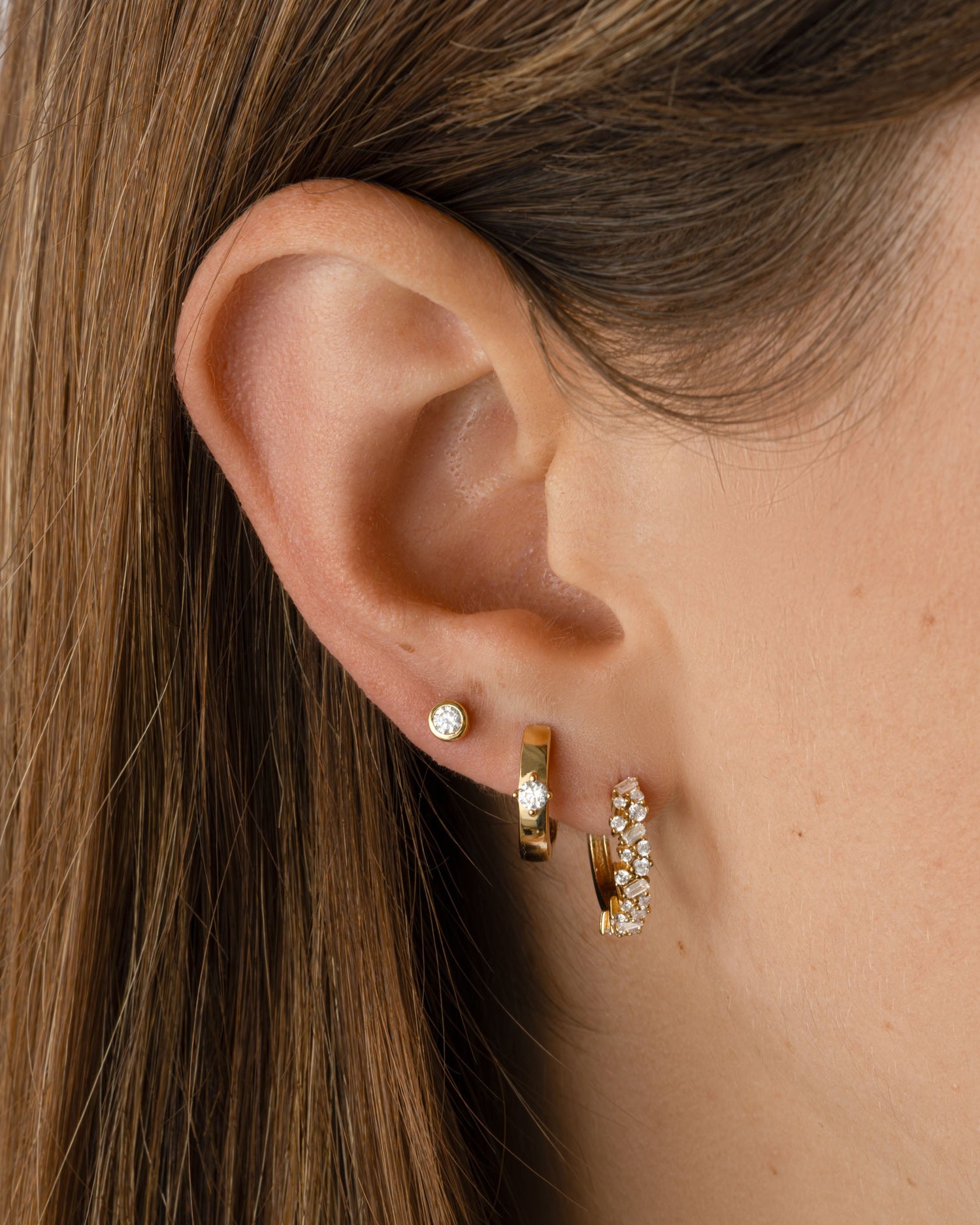 Sami Jewels Bella Huggie Hoop Earrings with diamond accents worn on a model, showcasing gold-plated design and elegant style.