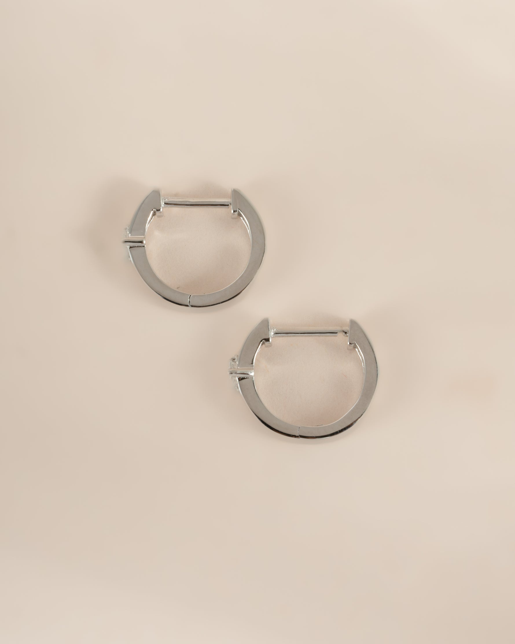Sami Jewels Bella Huggie Hoop Earrings with sparkling diamonds in sterling silver, shown in a side profile view.