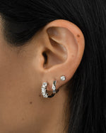 Sterling silver Bella Huggie Hoop Earrings with diamond accents, designed by Sami Jewels, close-up view of the jewelry.