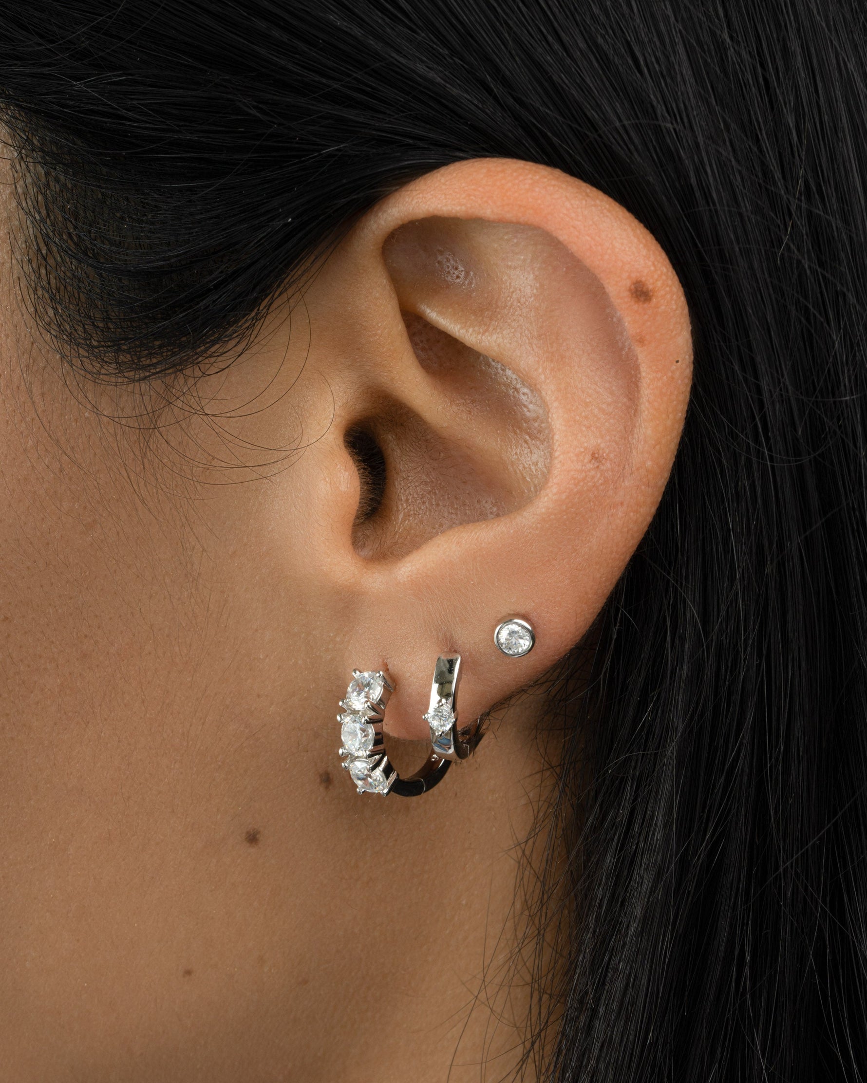 Sterling silver Bella Huggie Hoop Earrings with diamond accents, designed by Sami Jewels, close-up view of the jewelry.