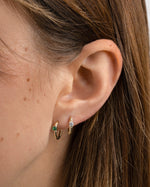 diamond spiral huggies in white cz and emerald stone on model in gold 