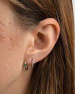 diamond spiral huggies in emerald stone and white cz stone on model in sterling silver
