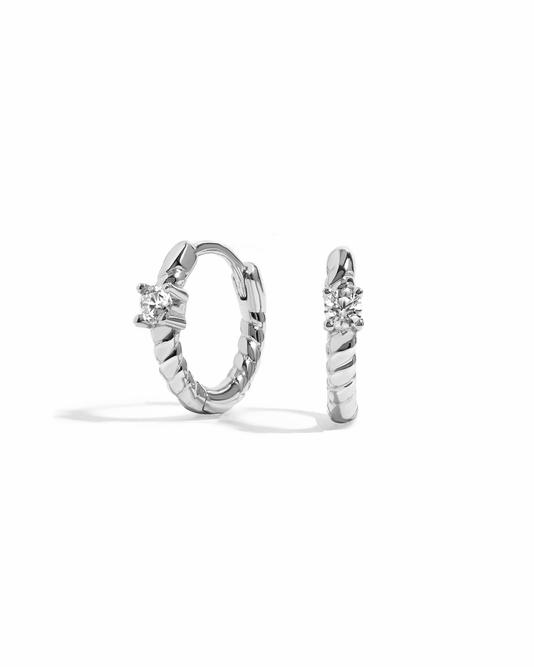 Sterling silver diamond spiral huggie hoop earrings by Sami Jewels displayed against a white background.