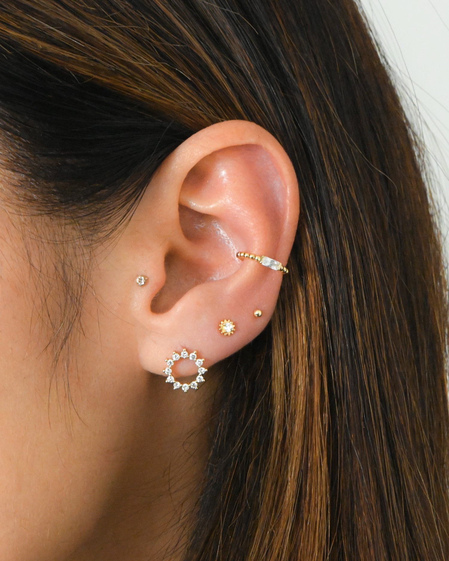 Gold CZ Tiny Sunburst Stud Earrings by Sami Jewels featuring small, sparkling sunburst design on classic studs.