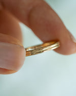 Close-up of Sami Jewels gold double band ring showcasing sleek, intertwined design on a plain background.