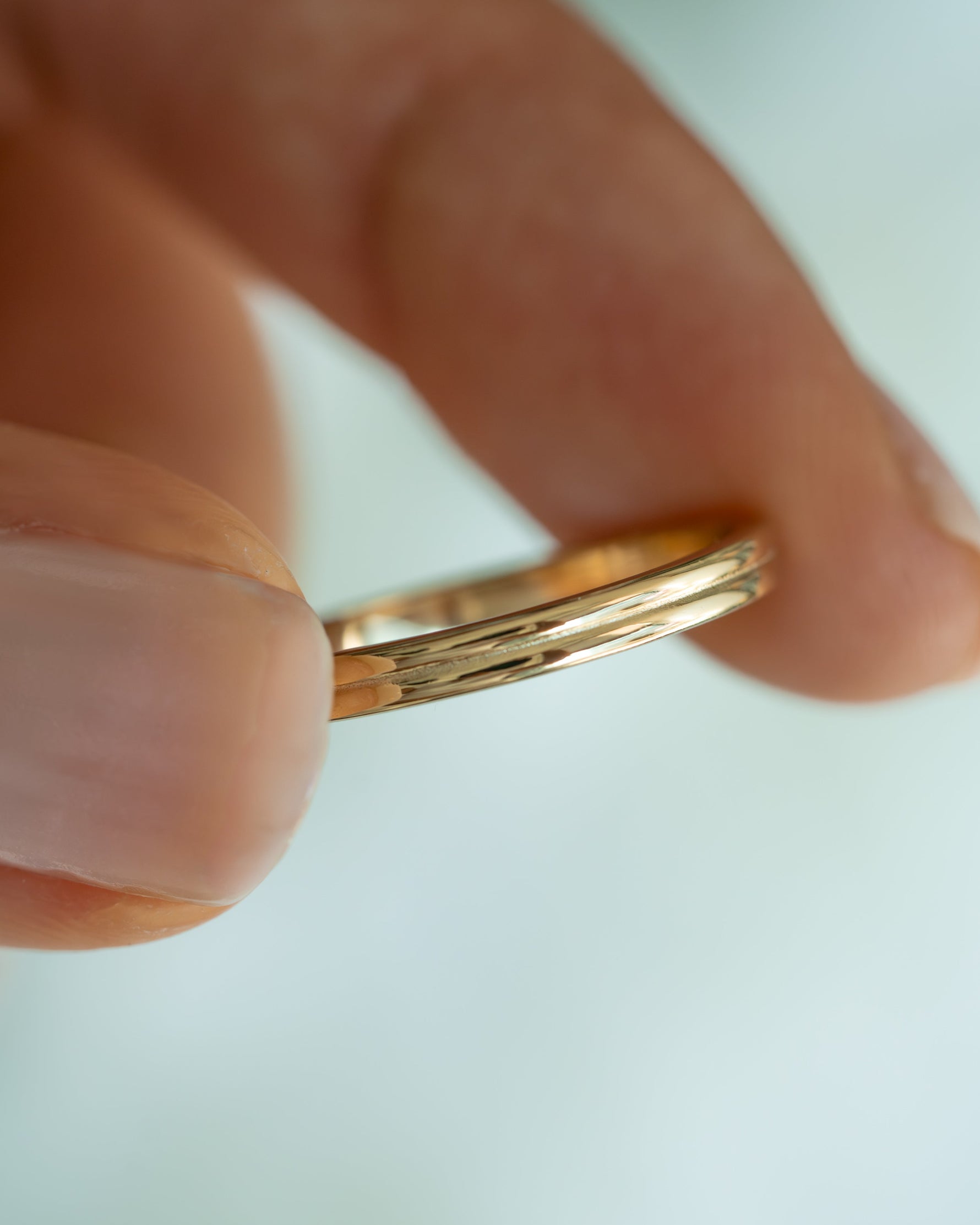 Close-up of Sami Jewels gold double band ring showcasing sleek, intertwined design on a plain background.