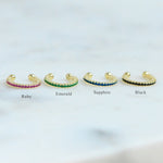 ear cuffs on a simple background in ruby, emerald, sapphire, and black