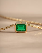 Close-up of Samijewels-527 emerald baguette bezel statement necklace with gold setting, showcasing detailed craftsmanship and vibrant green stones.