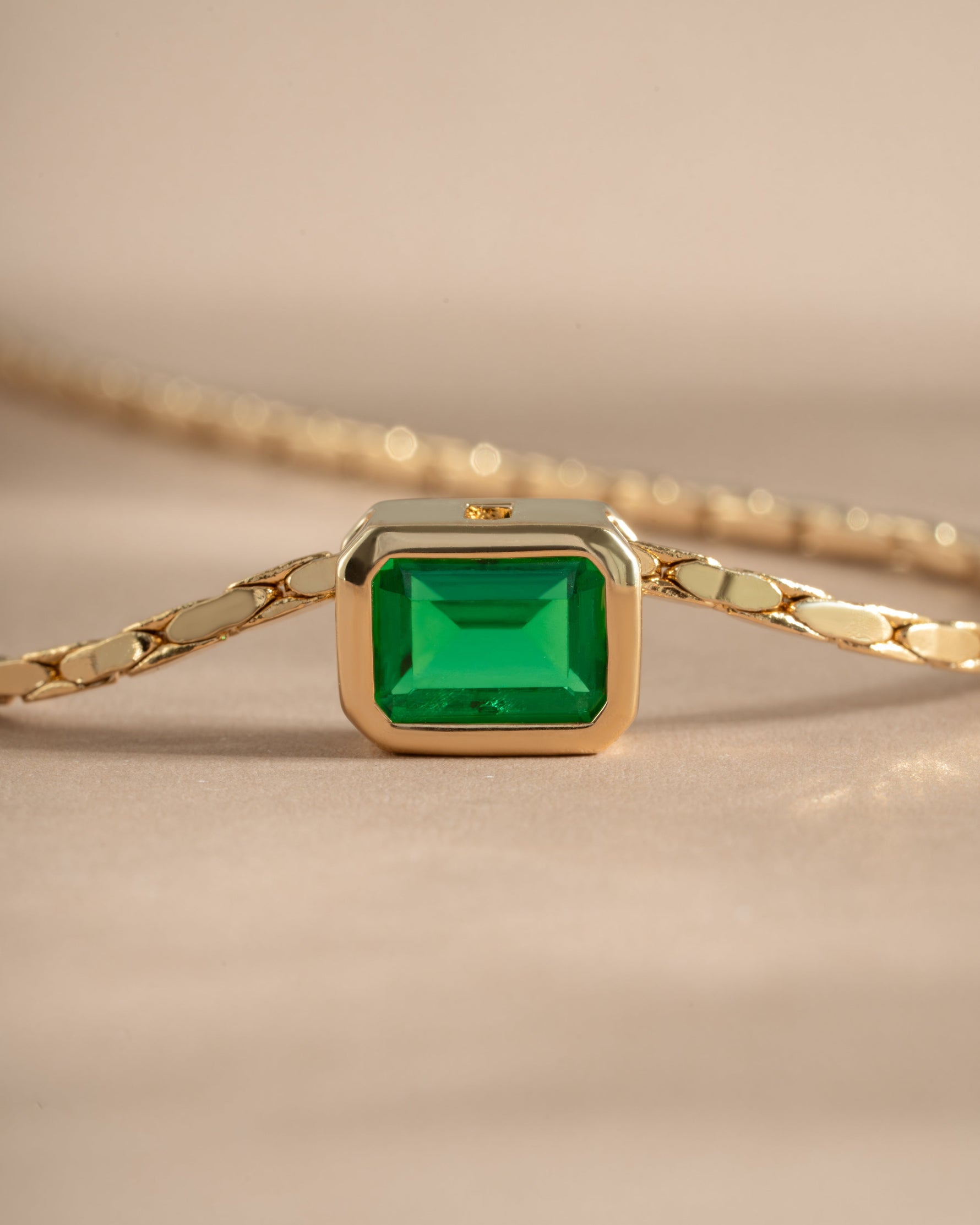 Close-up of Samijewels-527 emerald baguette bezel statement necklace with gold setting, showcasing detailed craftsmanship and vibrant green stones.