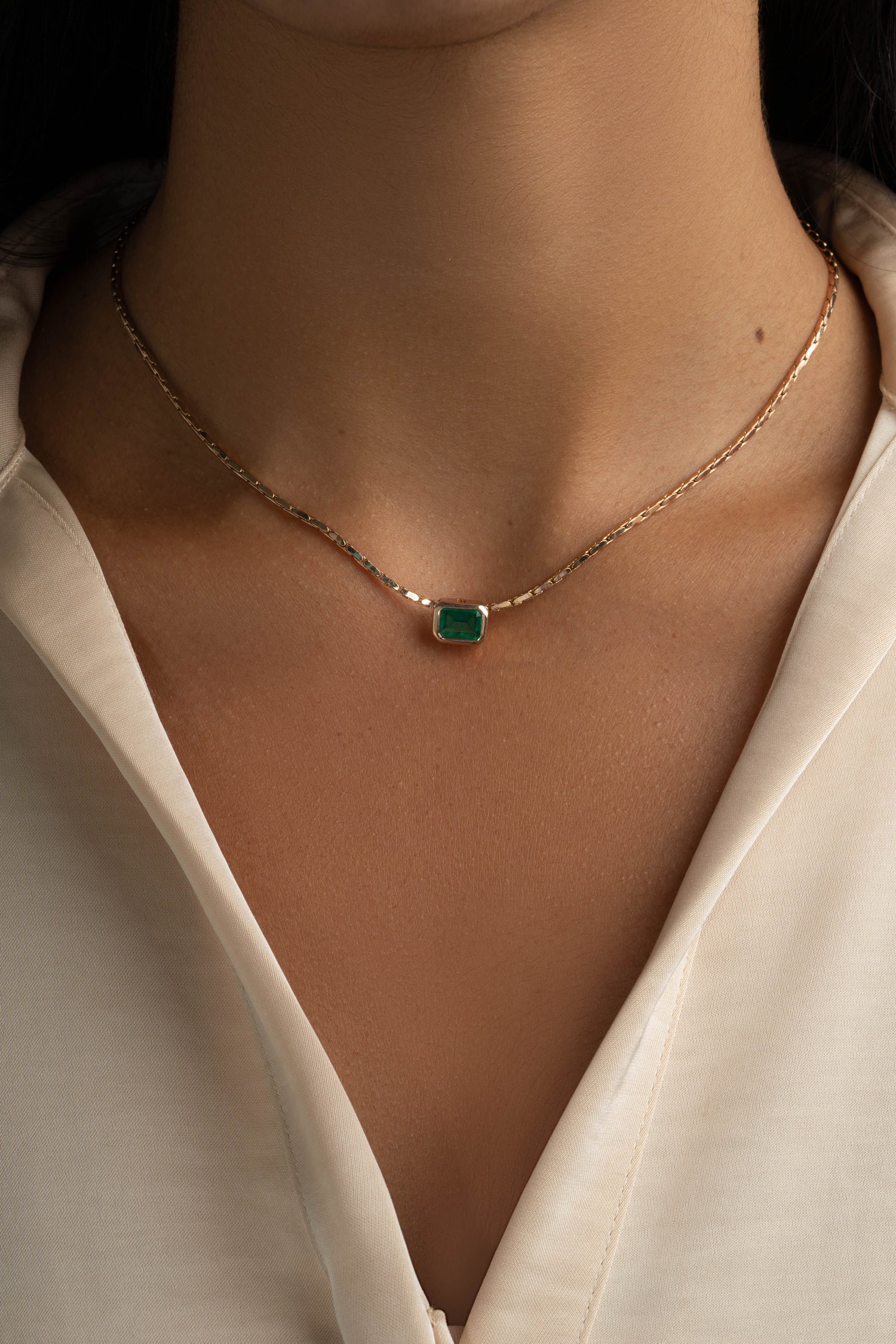 Gold Emerald Baguette Bezel Statement Necklace by Sami Jewels featuring a bold green gemstone pendant on a gold chain.
