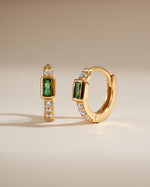 Gold Sami Jewels emerald baguette huggie earrings featuring sparkling emerald gemstones in a sleek hoop design.