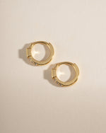 Gold emerald baguette huggie earrings by Sami Jewels, showcasing sleek hoop design with sparkling emerald gemstones.