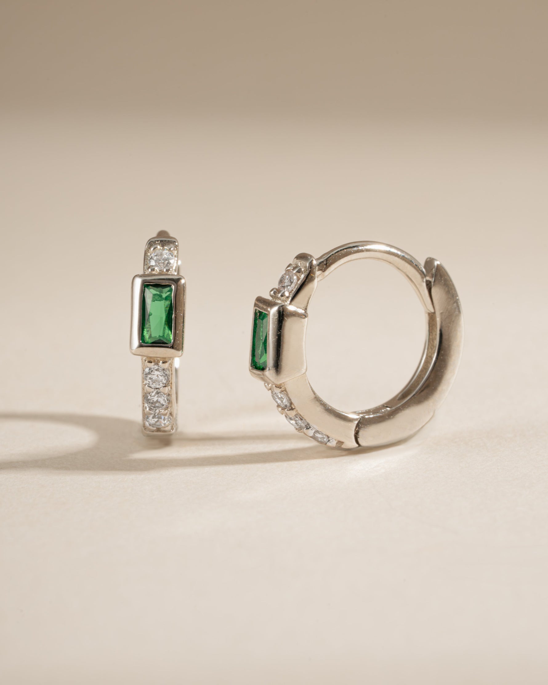 Side view of Sami Jewels emerald baguette huggie earrings in sterling silver, showcasing their sleek design and vibrant green gemstones.