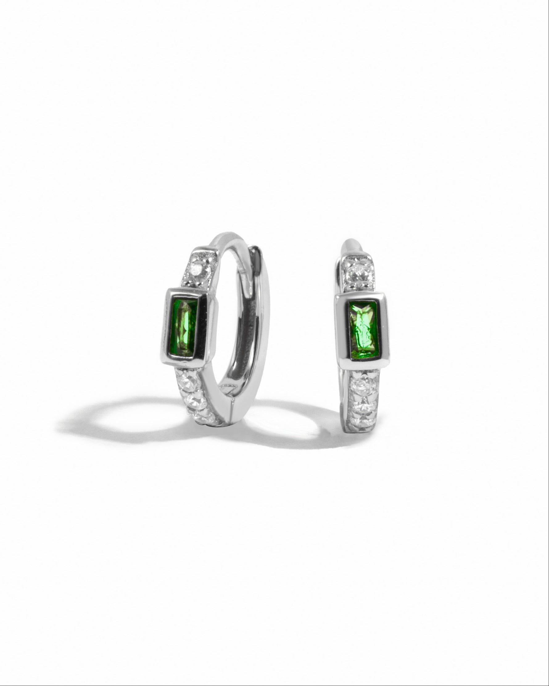 Sterling silver emerald baguette huggie earrings from Sami Jewels, featuring vibrant green rectangular gemstones on a white background.