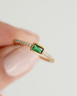 emerald baguette ring with pave band in gold held between fingers