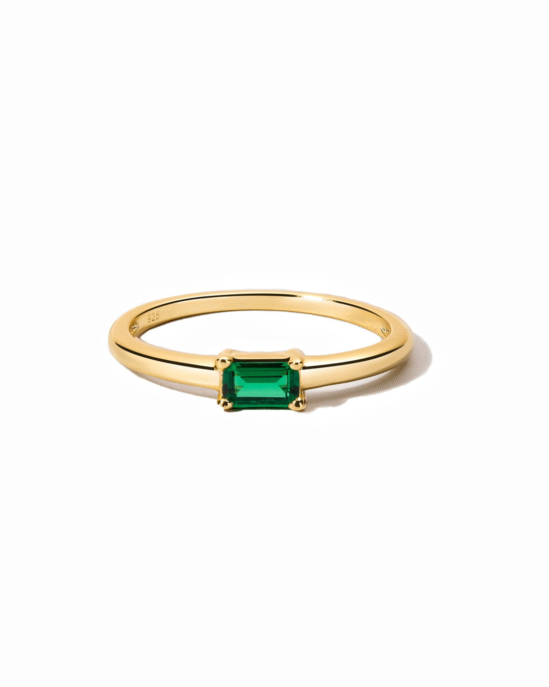 Gold emerald Lori Baguette ring by Sami Jewels featuring a central rectangular emerald gemstone on a white background