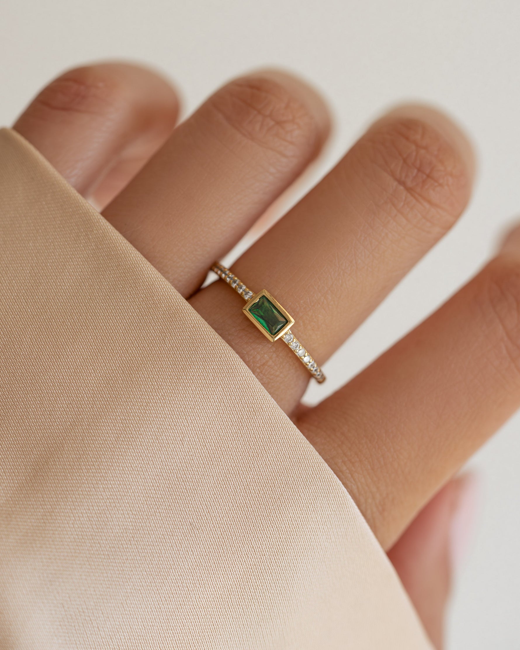 emerald baguette ring with pave band in gold on models hand 