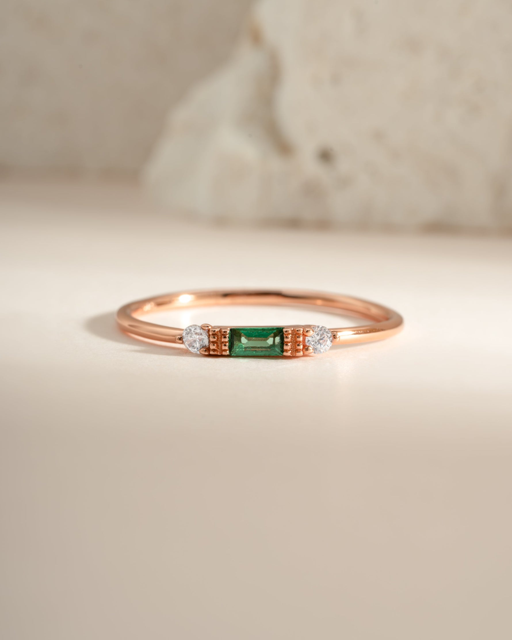 Sami Jewels emerald baguette ring with rose gold band featuring a rectangular emerald gemstone and elegant design.