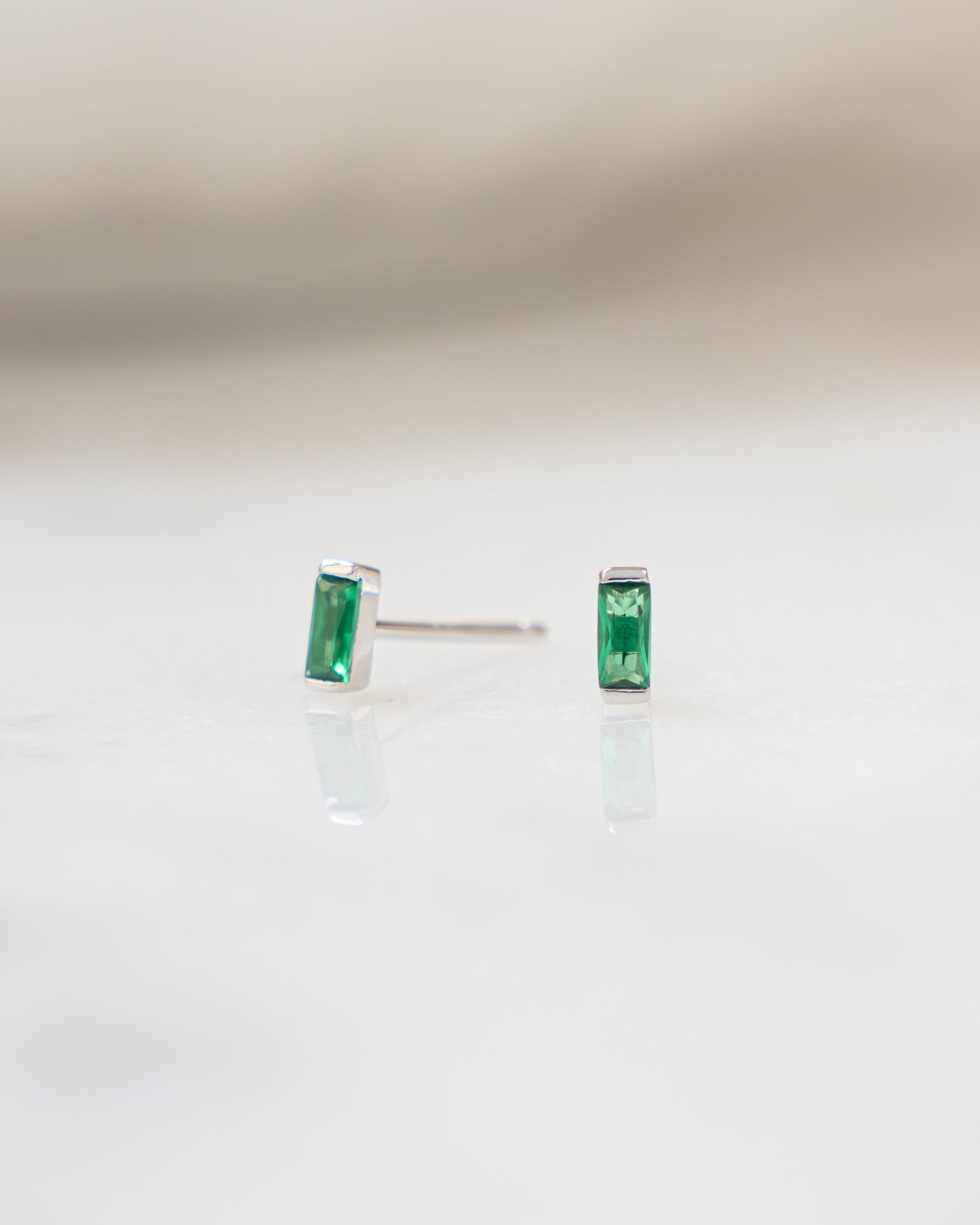 emerald baguette stud earrings in sterling silver with a blurred background