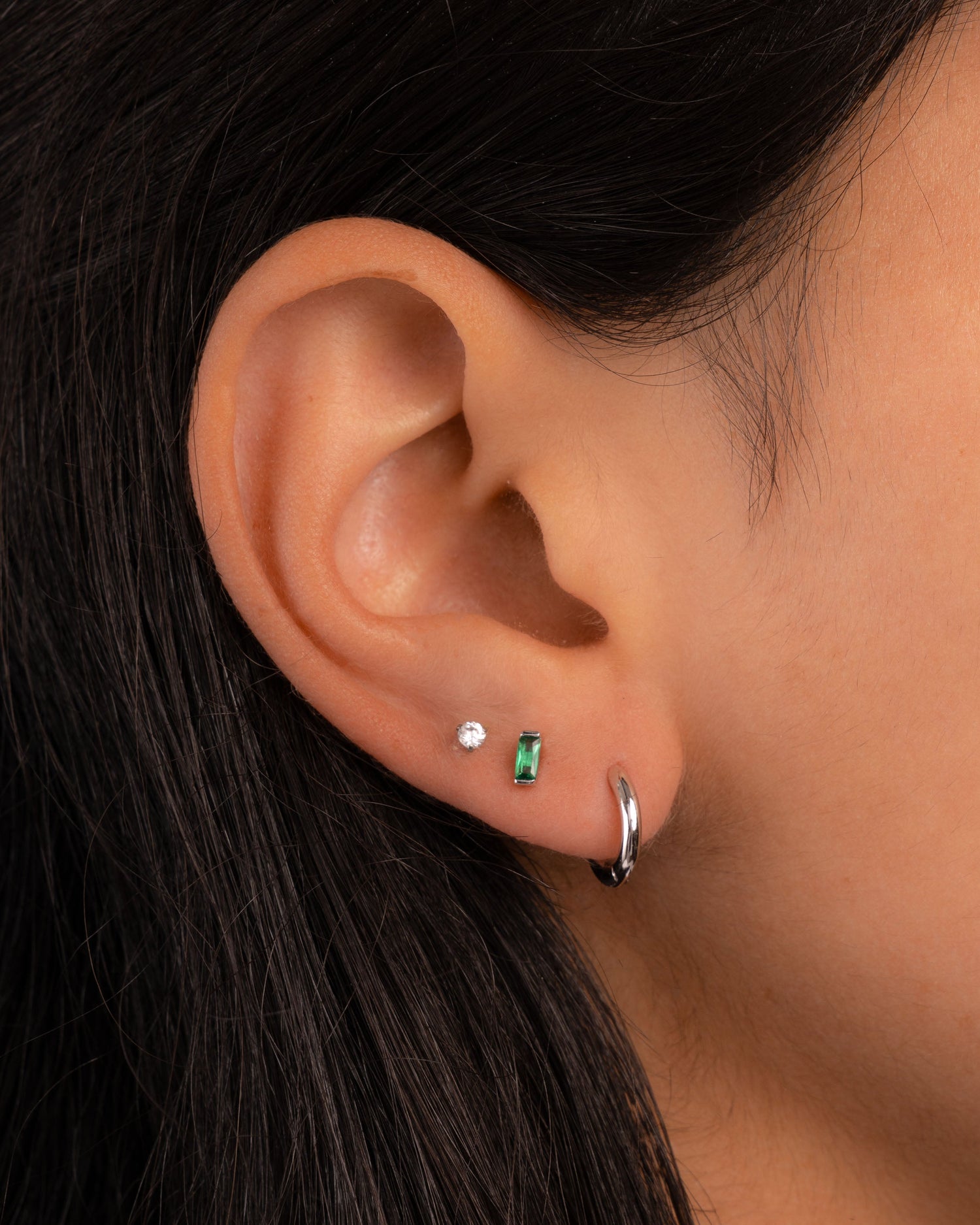 emerald baguette stud earrings in sterling silver on models ear in her second hole piercing