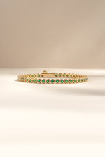 Detail of round green bezel settings on emerald tennis bracelet, view 1