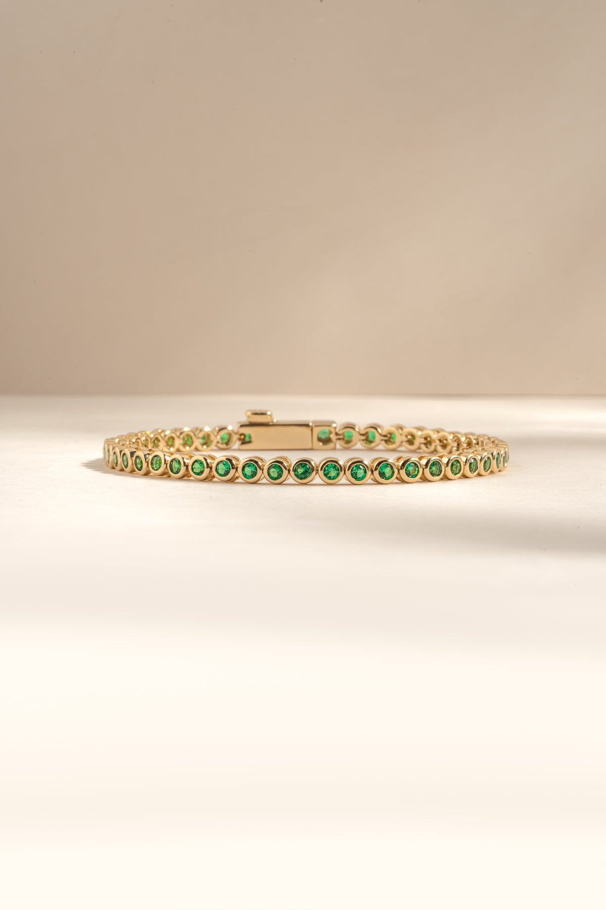 Detail of round green bezel settings on emerald tennis bracelet, view 1
