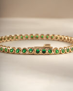 Detail of round green bezel settings on emerald tennis bracelet, view 2