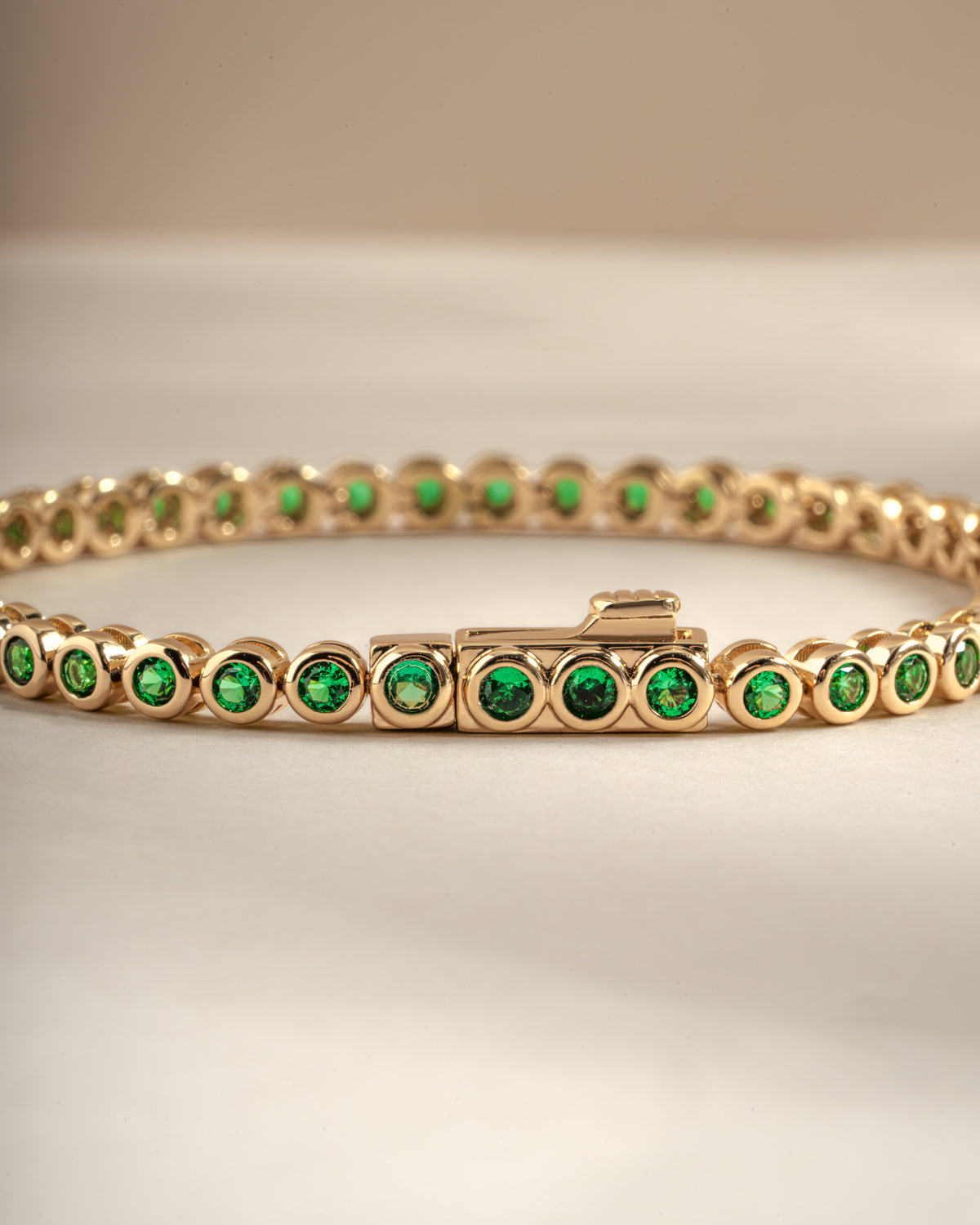 Detail of round green bezel settings on emerald tennis bracelet, view 2