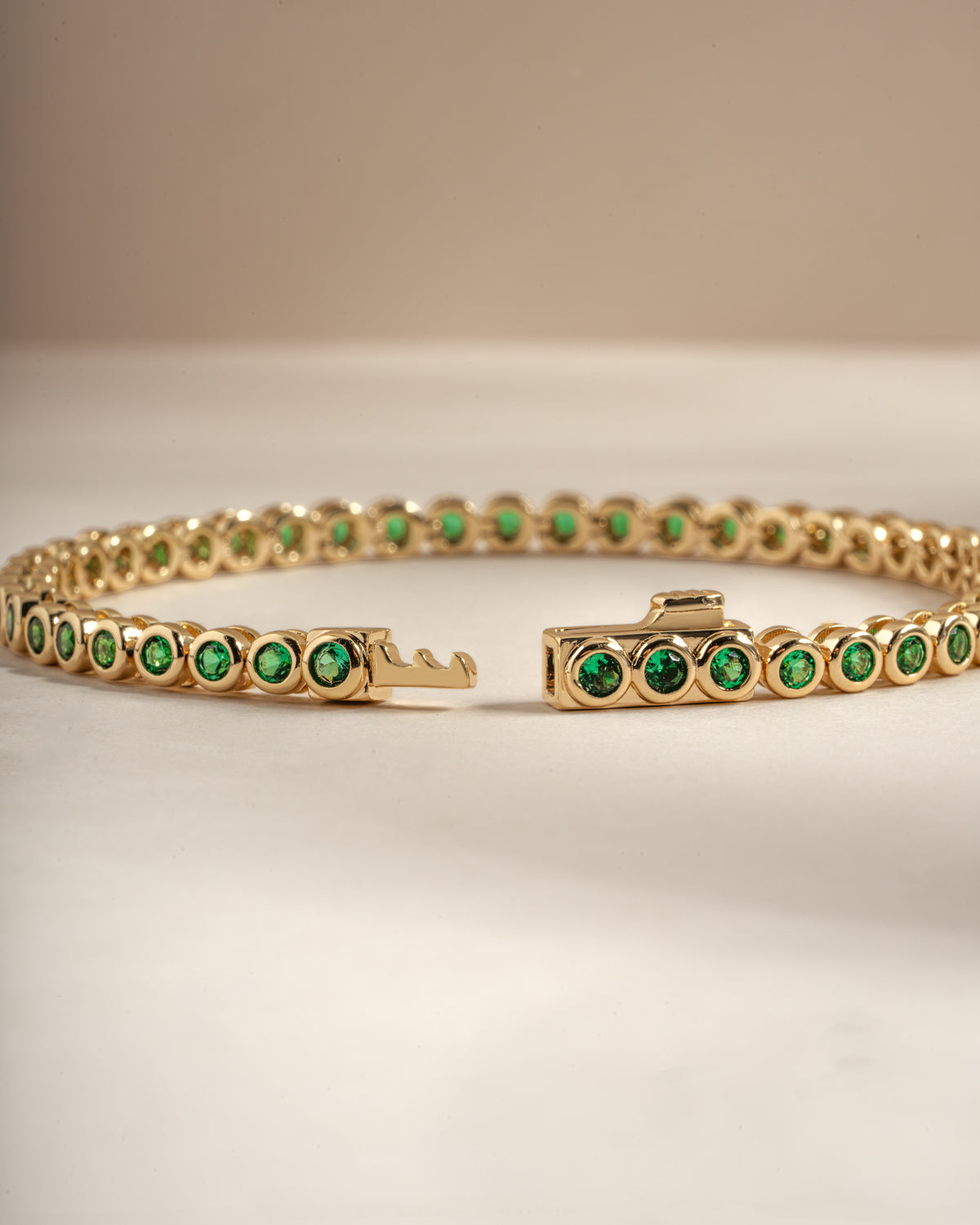 Detail of round green bezel settings on emerald tennis bracelet, view 3