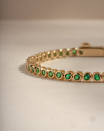 Detail of round green bezel settings on emerald tennis bracelet, view 4