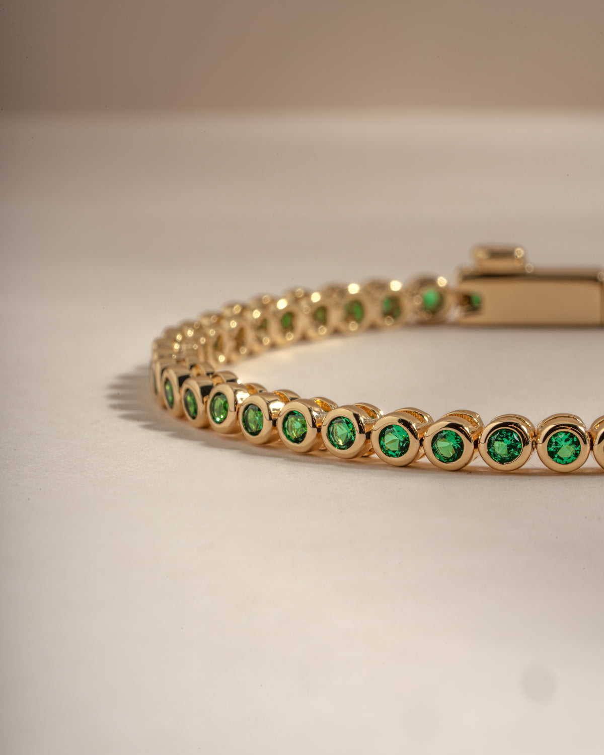 Detail of round green bezel settings on emerald tennis bracelet, view 4