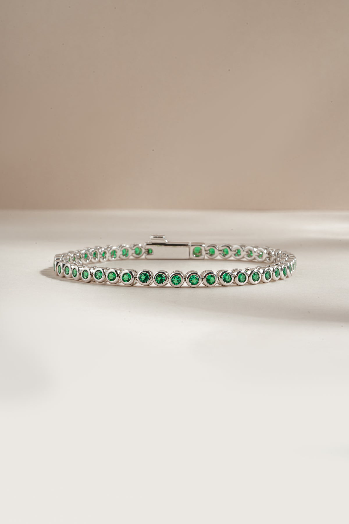 Detail of round green bezel settings on emerald tennis bracelet, view 5