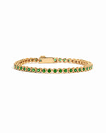 Gold plated emerald bezel tennis bracelet with round green stones on white background