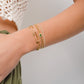 model wearing gold star charm bracelet, chain link bracelet, emerald halo charm on curb chain bracelet, and diamond tennis bracelet