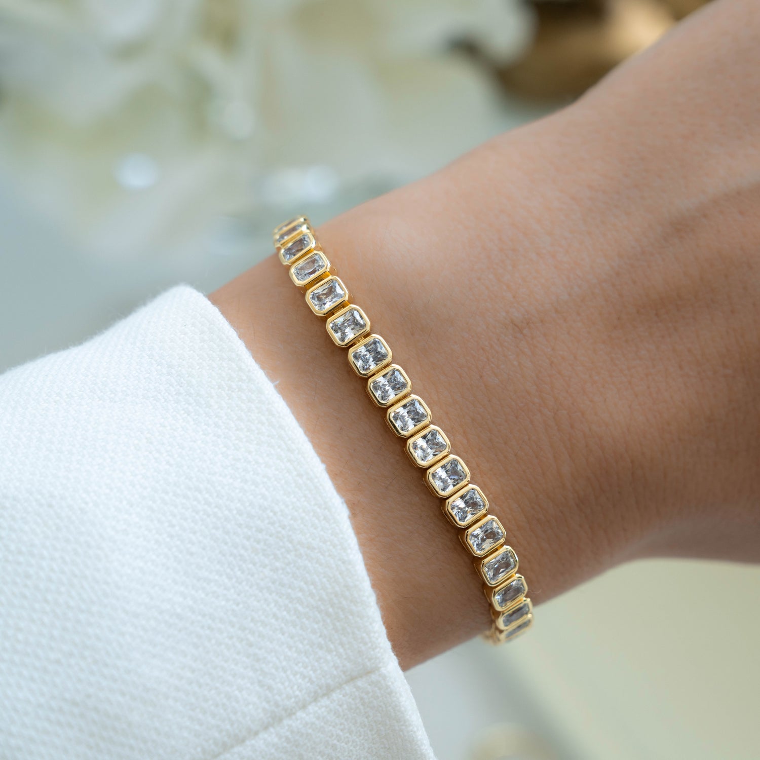 Gold emerald-cut bezel tennis bracelet by Sami Jewels, featuring sleek design and sparkling gemstone accents.