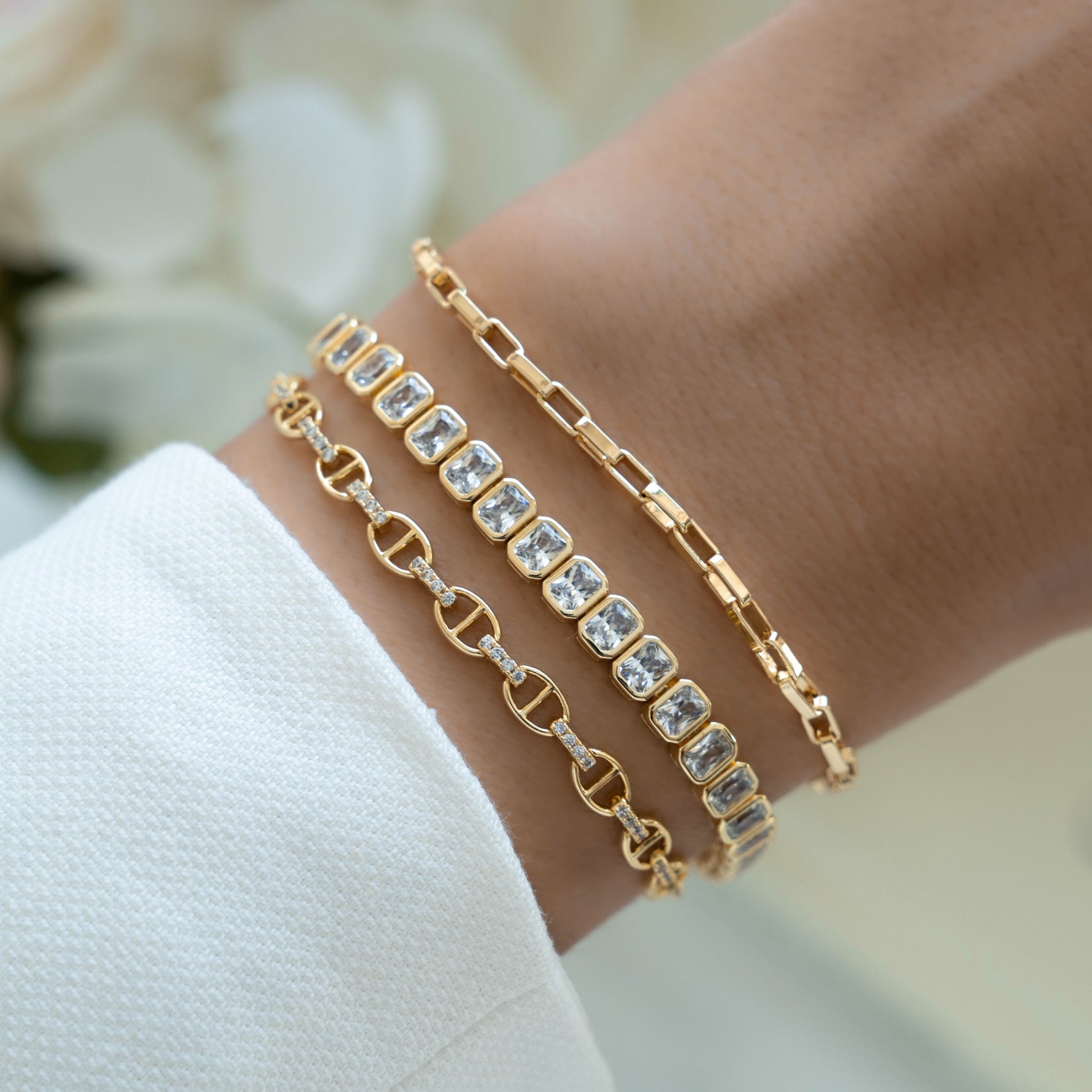 Gold Sami Jewels emerald-cut bezel tennis bracelet worn on a model, showcasing elegant jewelry design and sparkling gemstone setting.