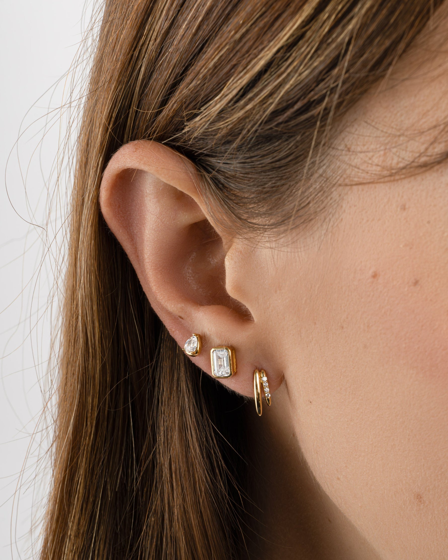 Gold emerald-cut stud earrings by Sami Jewels displayed on a styled model, showcasing their elegant and sparkling gemstone design.