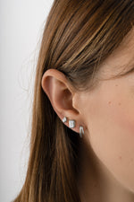 Sterling silver emerald cut stud earrings from Sami Jewels, showcasing sleek, rectangular gemstone design on a model.