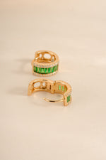 Emerald diamond baguette huggie hoops earrings by Sami Jewels featuring gold setting and sparkling green emerald accents.