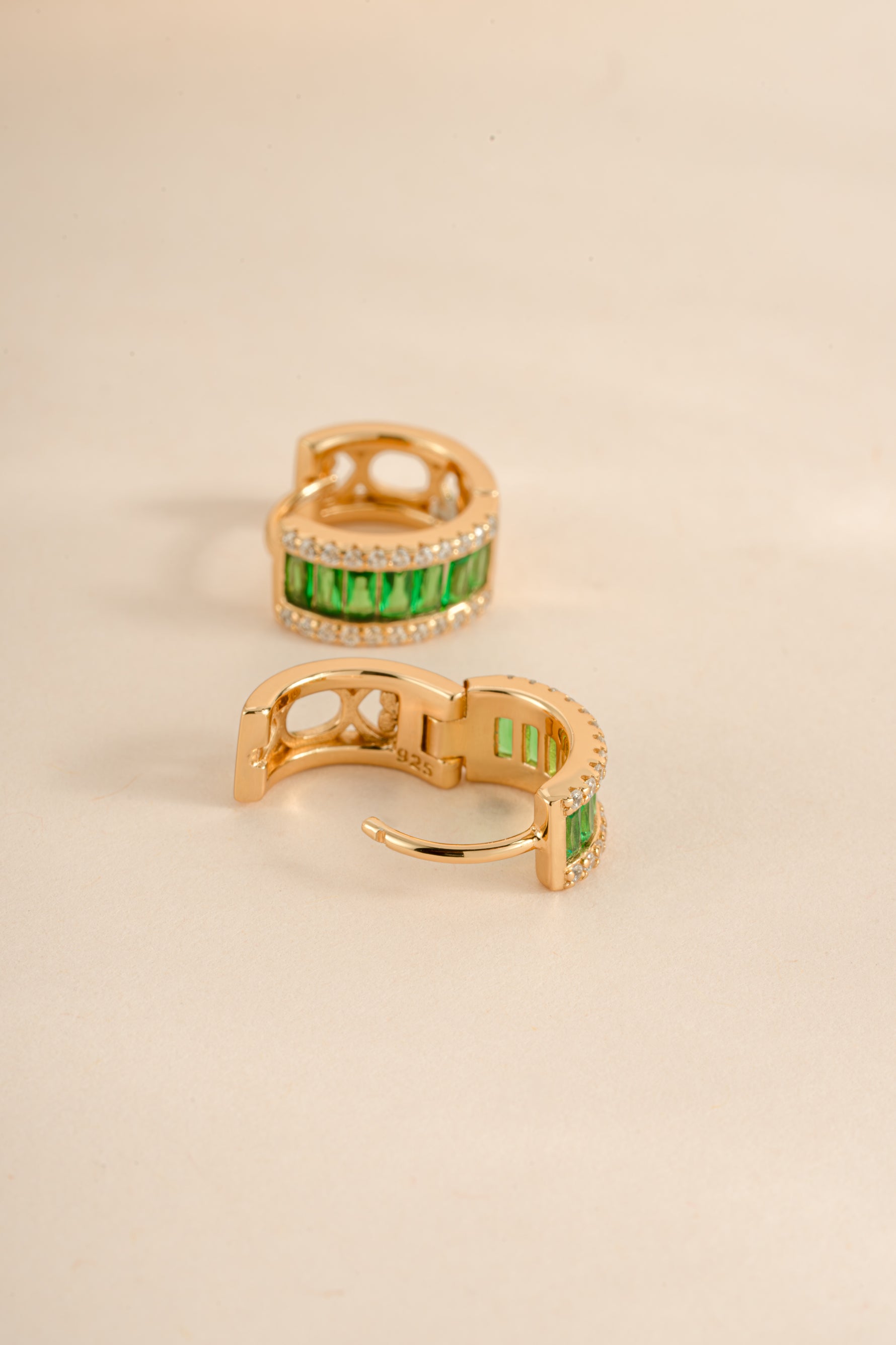 Emerald diamond baguette huggie hoops earrings by Sami Jewels featuring gold setting and sparkling green emerald accents.