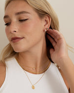emerald three stone huggie hoop earring in gold on model with gold jewelry