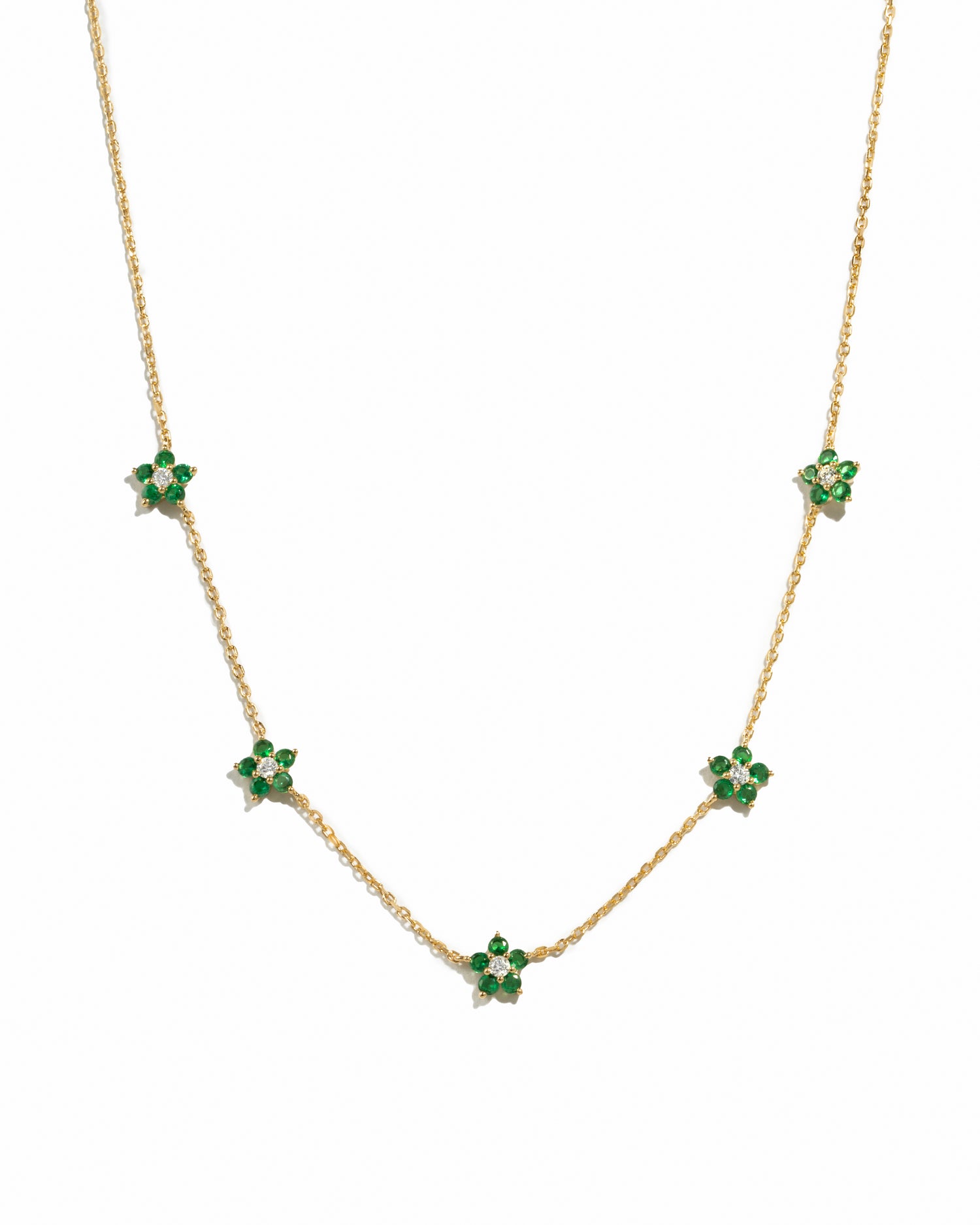 Gold necklace featuring a detailed emerald flower charm from Sami Jewels, displayed on a white background.