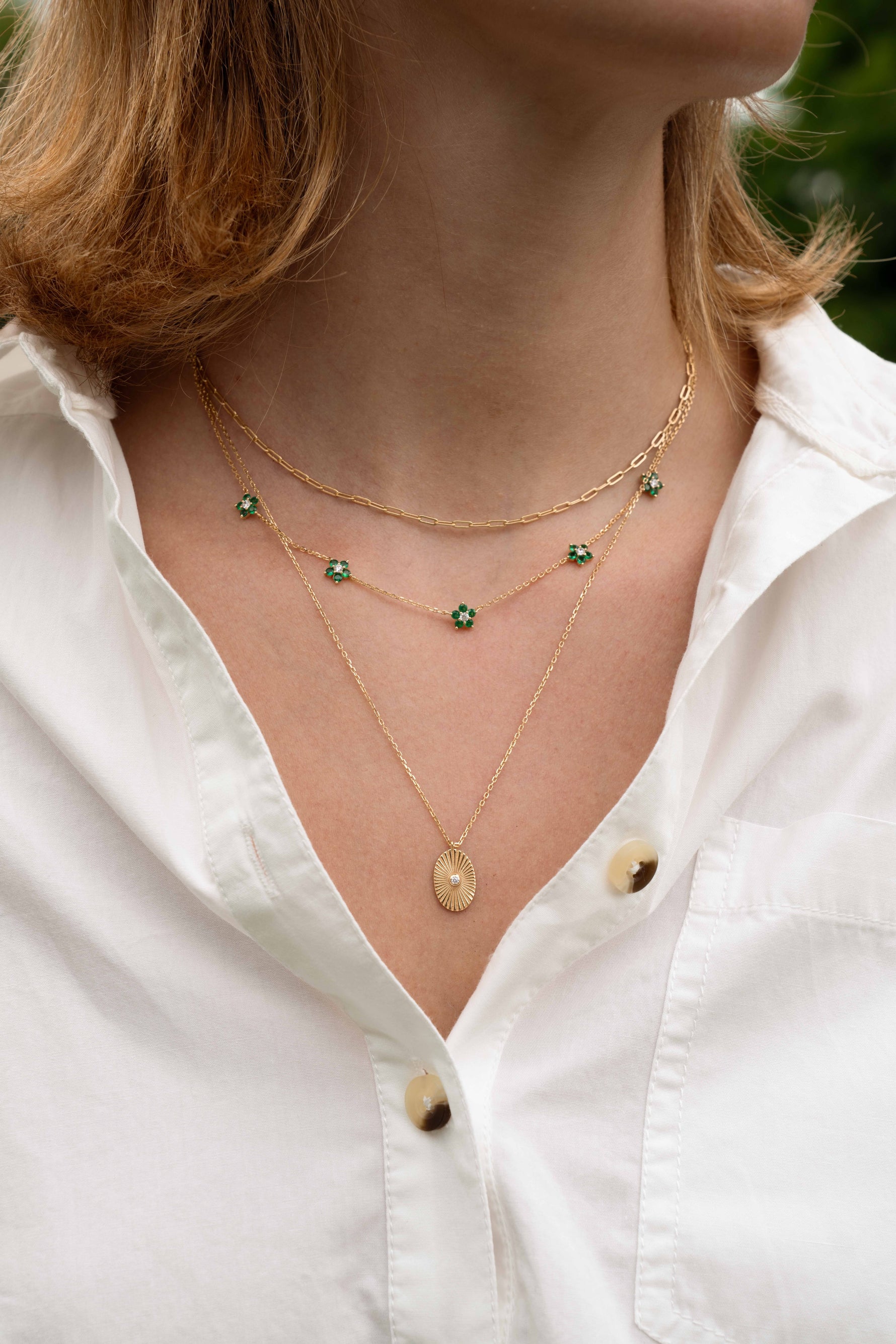 Gold emerald flower necklace from SJ Faire featuring a delicate floral design on a model.